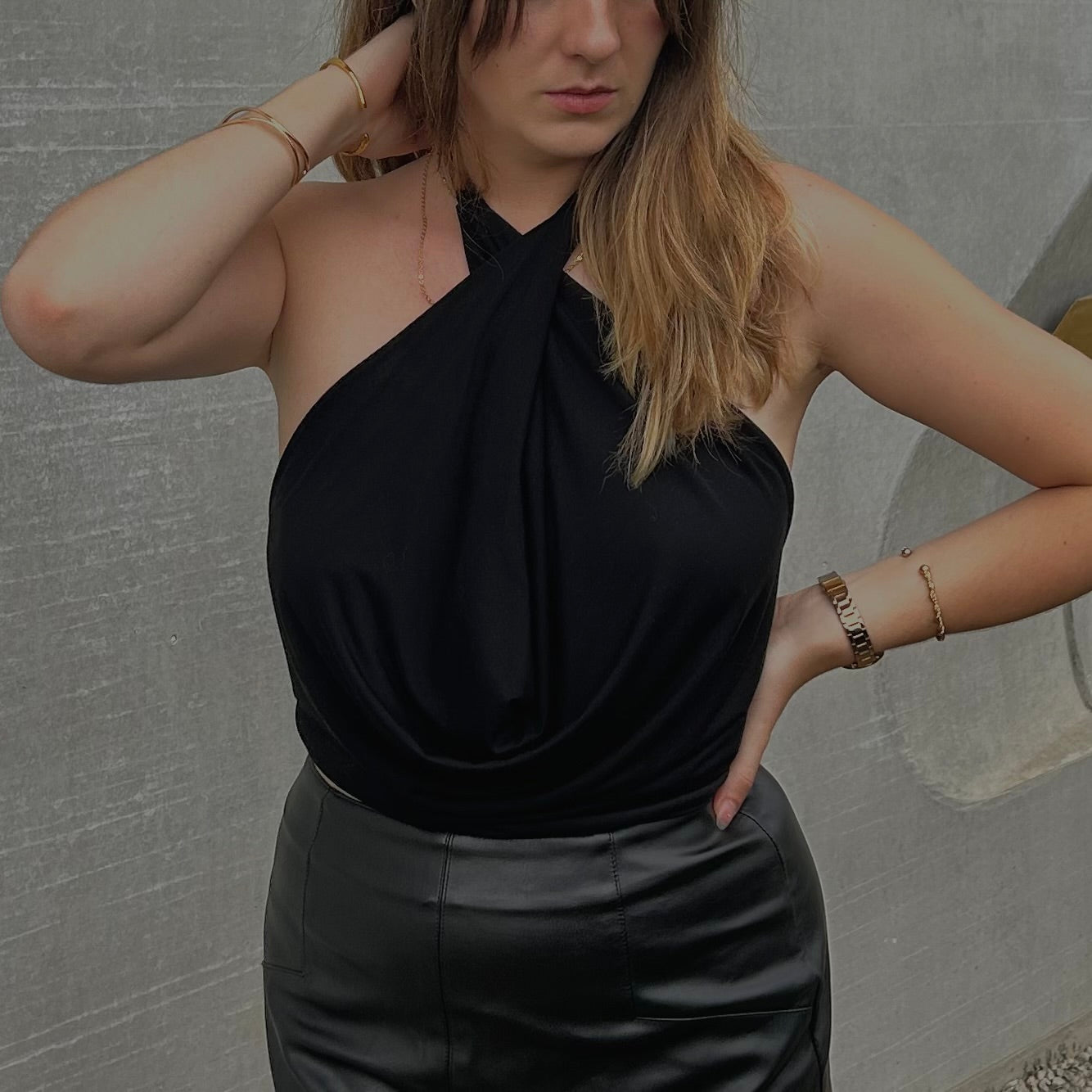Détail rapproché du système de lanières croisées et entrelacées à nouer sur le top modulable noir de la marque Bonjour Leoni. Haut porté par un modèle.