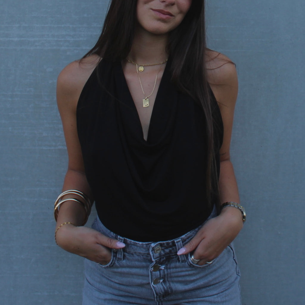 Gros plan sur le drapé fluide et élégant du haut ajustable noir de la marque Bonjour Leoni, porté par une femme en style col bénitier.