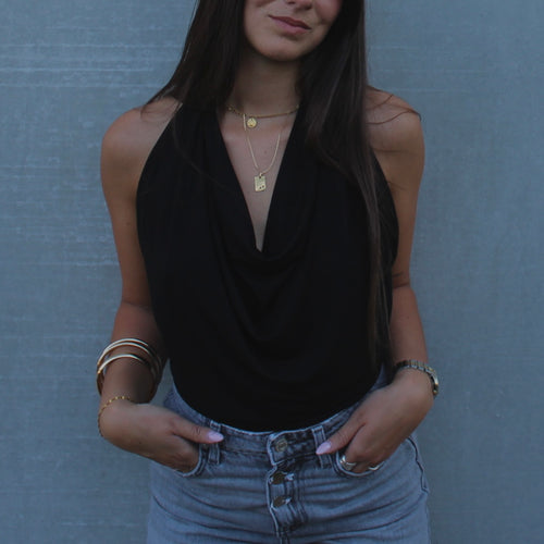 Gros plan sur le drapé fluide et élégant du haut ajustable noir de la marque Bonjour Leoni, porté par une femme en style col bénitier.