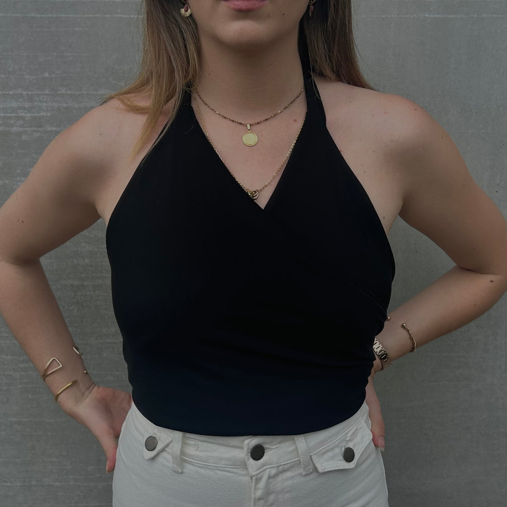 Focus sur le décolleté croisé du haut noir en Tencel de la marque Bonjour Leoni en version cache-cœur. Porté par une femme.