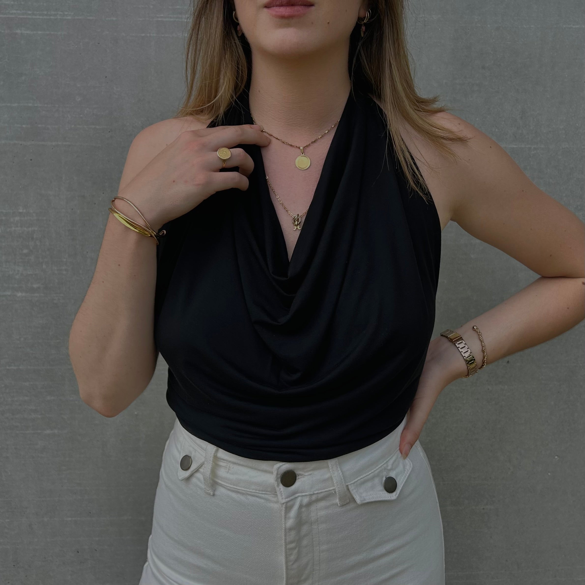 Focus sur la texture douce en jersey et les plis délicats du col bénitier sur le haut noir de la marque Bonjour Leoni. Porté par une femme.