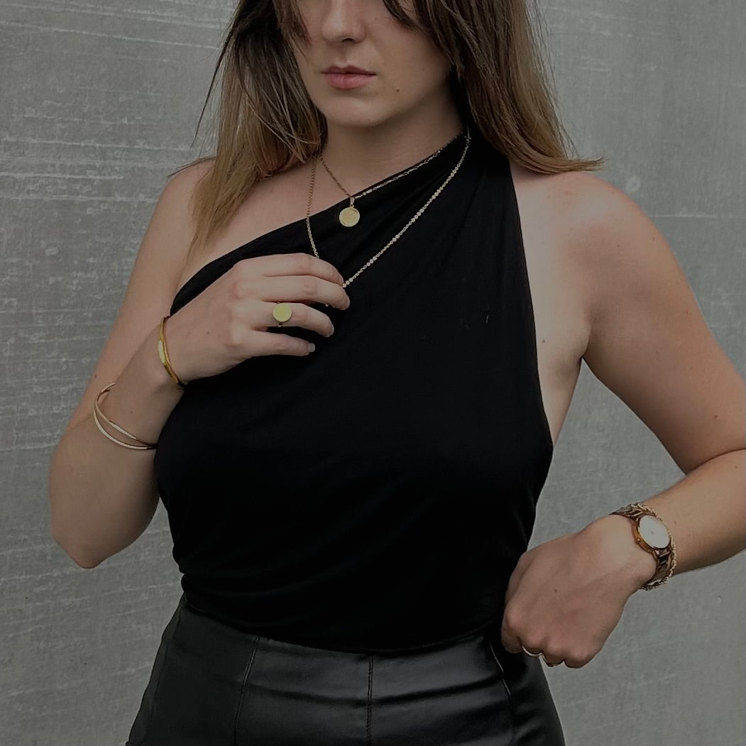 Gros plan sur le tombé graphique et la ligne d'épaule asymétrique du haut en Tencel écoresponsable et cousu main de la marque Bonjour Leoni. Porté par une femme.
